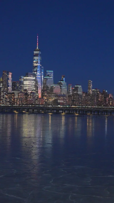 Lower Manhattan skyscraper stands beyond frozen Hudson River in dusk. Stock Footage 336653489