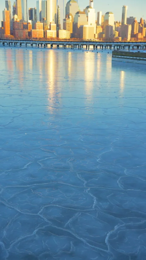 Lower Manhattan skyscraper stands beyond frozen Hudson River in dusk. Vídeo Stock 336653814