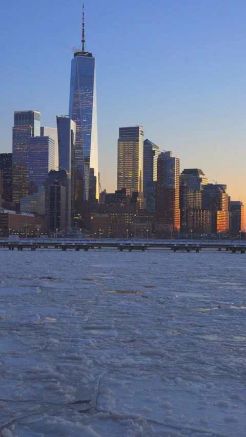 Lower Manhattan skyscraper stands beyond frozen Hudson River during twilight Vídeo Stock 336711860