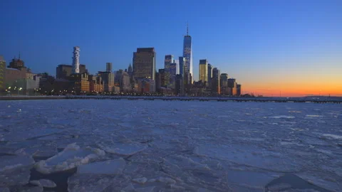Lower Manhattan skyscraper stands beyond frozen Hudson River during twilight Stockbeeldmateriaal 336712377