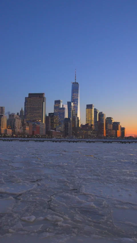 Lower Manhattan skyscraper stands beyond frozen Hudson River during twilight Vídeo Stock 336713125