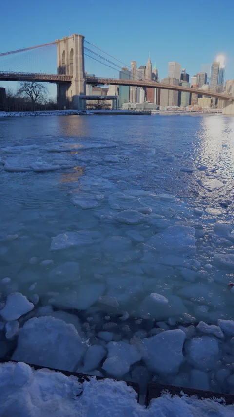 Lower Manhattan skyscraper stands beyond frozen Pebble Beach in Brooklyn. Vídeo Stock 336815027