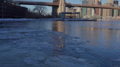 Lower Manhattan skyscraper stands beyond frozen Pebble Beach in Brooklyn. 動画素材 336815374
