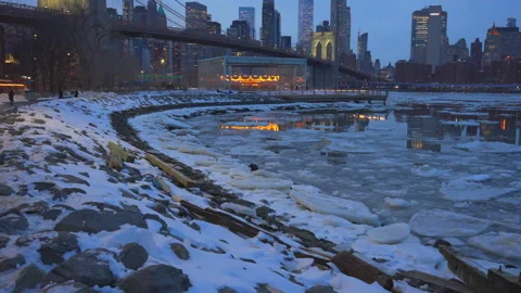 Lower Manhattan skyscraper stands beyond  frozen Pebble Beach in Brooklyn in NYC Vídeo Stock 337005146