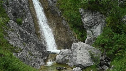 The lower part of a waterfall runs into a pool between rocks (slow motion) Video stock 260845225