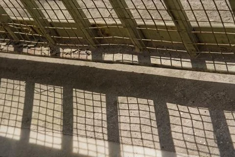 Lower portion of iron gate sealed with net and its shadow on ground Stock Photos