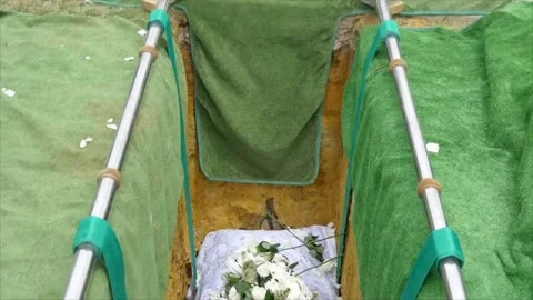 Lowering of the casket coffin into the burial ground at the cemetery Stock Footage 303385961