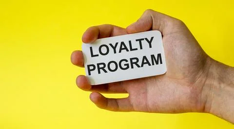 Loyalty program card in hand isolated on yellow background Stock Photos