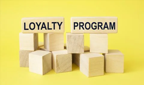 Loyalty program text on wooden blocks and on yellow table Fotos de archivo