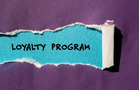 Loyalty program words written on purple torn paper with blue background 스톡 사진