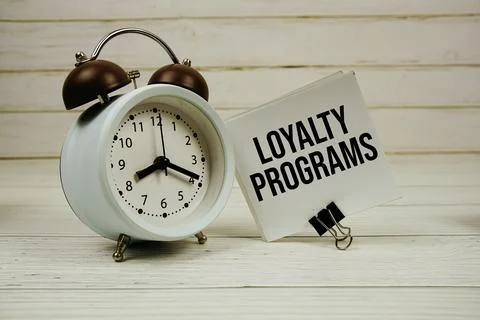 Loyalty Programs text message on sticky note with alarm clcok on wooden bac.. Stock Photos