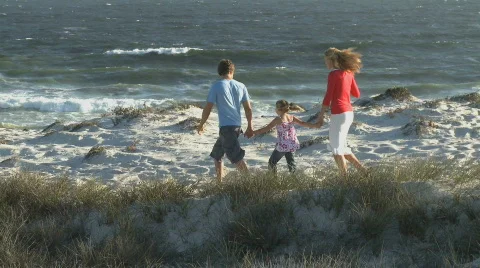 LS PAN OF A FAMILY WALKING ALONG A BEACH Stock Footage