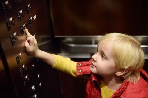 Lttle boy pressing button of lobby in elevator Foto stock