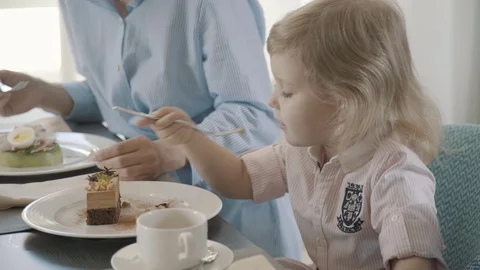 Lttle sweet girl eats herself at the table with her parents. Stock-Footage 77287225