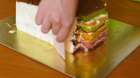 Lubricate the biscuit cake with multi-colored cake layers with butter cream Stock Footage 108558071