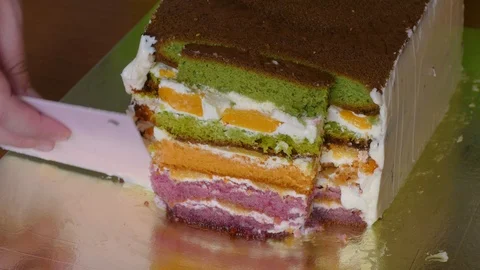 Lubricate the biscuit cake with multi-colored cake layers with butter cream Stock-Footage 108558855