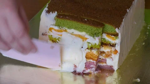 Lubricate the biscuit cake with multi-colored cake layers with butter cream Video stock 108559205
