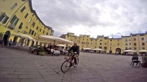 Lucca - Man rides through a piazza in the centre of the city. Video stock 99552139