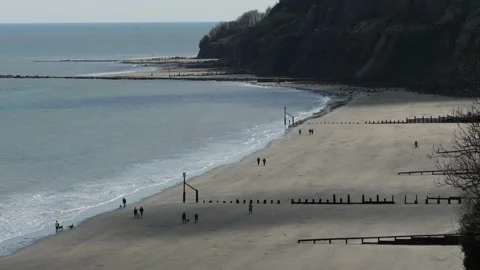 Luccombe beach at low tide with few people and dramatic cliff backdrop, UK Stock Footage 238701642