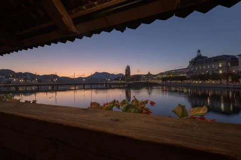 Lucerne cityscape at dusk with river reflections and wooden foreground detail Stock Photos