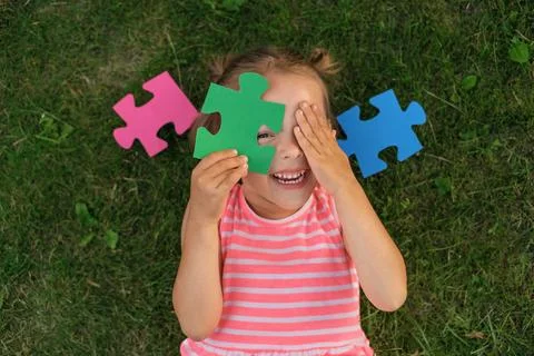 A ludicrous child is playing with puzzles while lying on the lawn grass Stock Photos