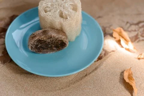 Luffa sponge on a ceramic blue trowel. Background sand and craft paper. Foto stock