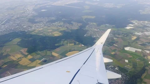 Lufthansa airplane wing view during flight over patchwork fields, towns and Stock Footage 340369080