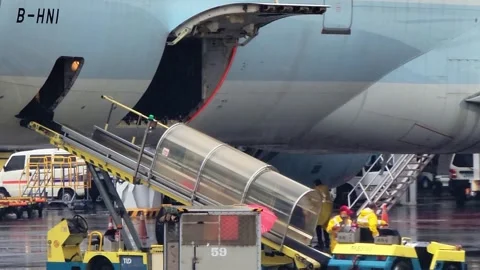 Luggage off-loading from a plane after the cart arrive, under heavy rain 스톡 동영상 252437851