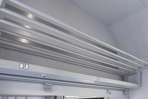 A luggage rack inside a modern passenger train cabin featuring metal rails for 스톡 사진