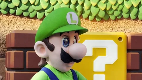 Luigi mascot poses by a Question Block at Super Nintendo World, Universal Studio Stock Footage 334266232