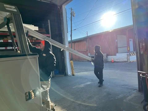 Lumber Yard Employees Loading Material on a customer’s truck in the winter. Stock Photos