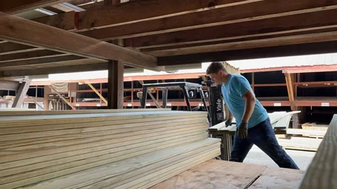 Lumber Yard Worker Stacking Treated Deck boards in a rack by hand Stock Footage 291983643