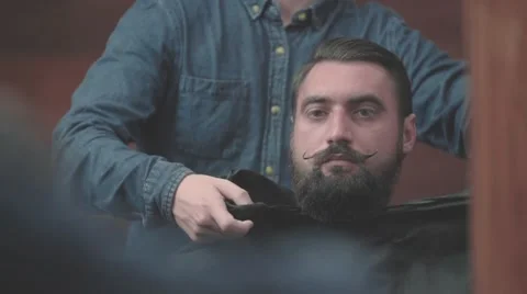 Lumberjack bearded man looking to mirror in barbershop HD slow motion video Stock Footage 68378096