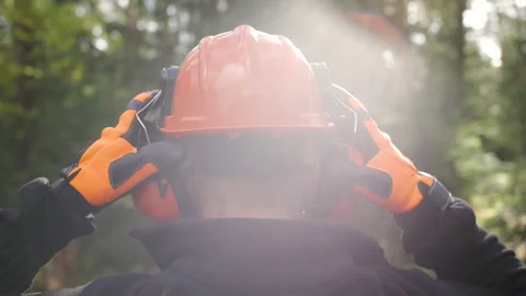 Lumberjack in the forest puts on a protective helmet Stock Footage 184077163