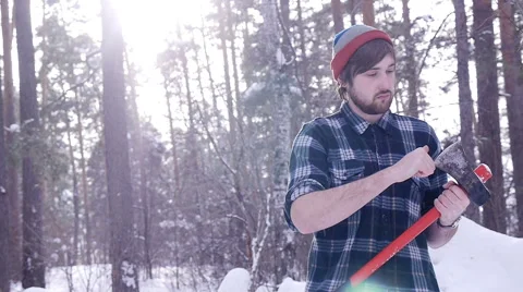 Lumberjack stands and sharpens his ax in the woods, light leakage surround him Stock Footage 60049725
