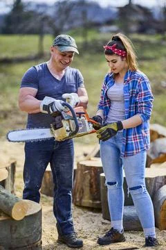 Lumberjack teaches his apprentice how to use the chainsaw Stock Photos