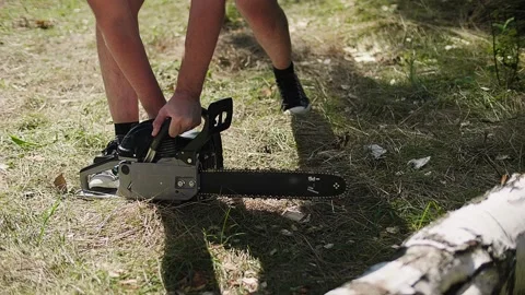 Lumberman starts working, launch the chainsaw engine on the green grass field Video stock 145239299