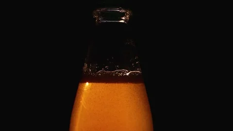 A luminous amber liquid inside a glass bottle on black background lighting Stock Footage 320418843