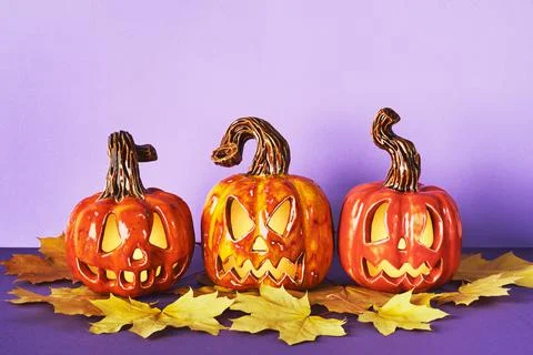 Luminous Ceramic Pumpkin jack lanterns with yellow autumn leaf on purple back Stock Photos