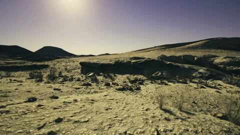 Luminous dry terrain extending to distant mountain peaks with textured stones Stock Footage 340662432