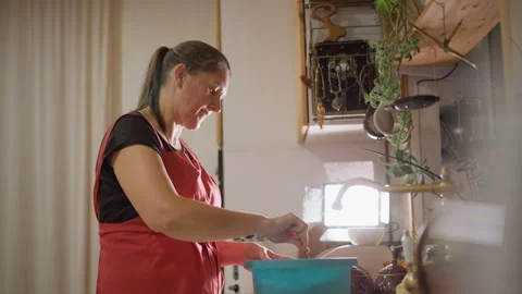 Luminous kitchen environment featuring baker stirring batter happily. Cozy Stock-Footage 346409496
