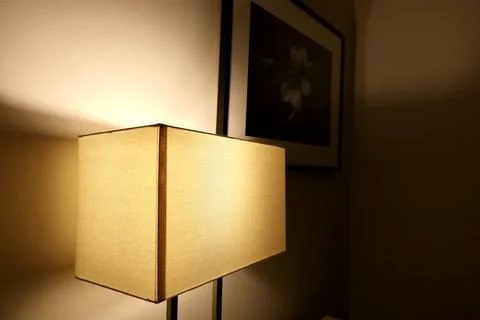 A luminous lamp with a rectangular lampshade near the wall Stock Photos