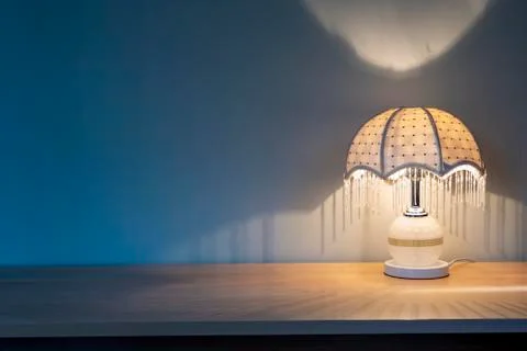 A luminous lamp in the shadow, a table lamp on the desk Stock Photos