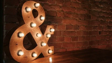 Luminous lamp in the shape of &amp; on the background of a brick wall Stock Footage 86076359