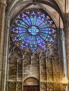 Luminous rays filtering through ornate rose window, casting kaleidoscopic l.. Stockfoto's