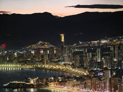 Luminous skyline with diverse architecture reflected in tranquil waters during Stock Photos
