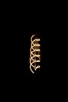 Luminous thread of a retro Edison lamp on a dark background Stock Photos