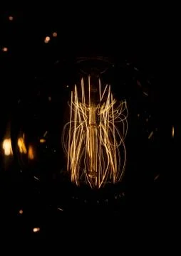 Luminous thread of a retro Edison lamp on a dark background Stock Photos