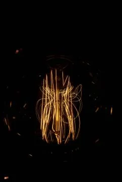 Luminous thread of a retro Edison lamp on a dark background Stock Photos