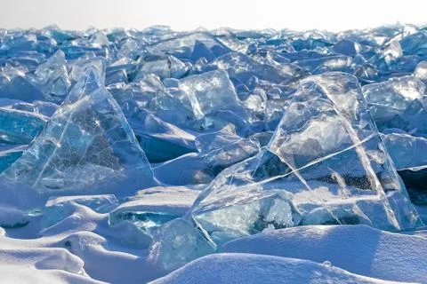 Luminous transparent triangle ice blocks on ice field background Stockfoto's
